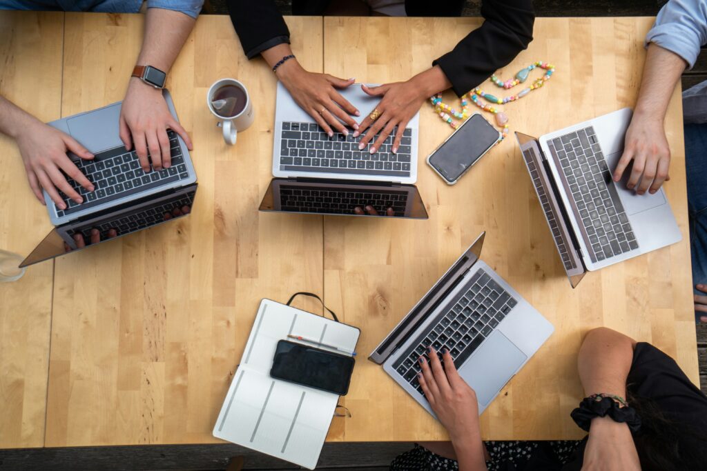 Overview of hands working on laptops at table 