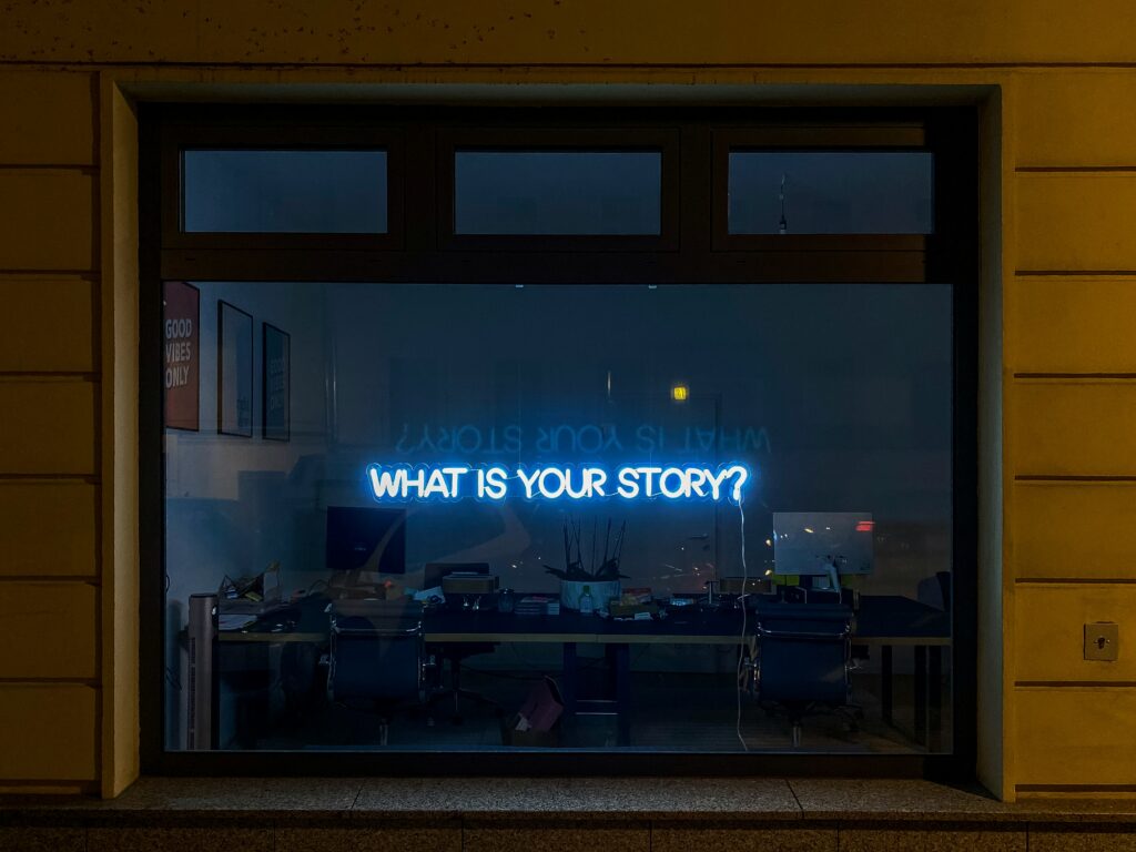 Window with neon light that says what is your story?